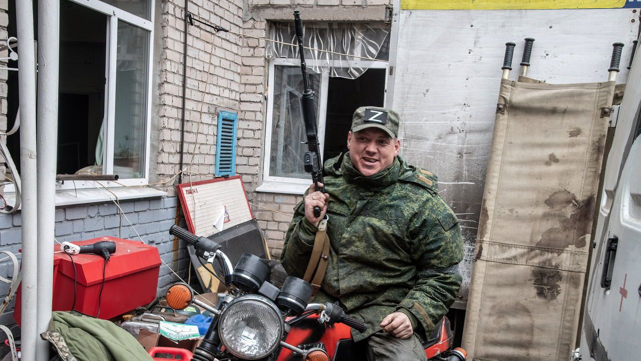 A Donetsk People's Republic soldier poses on a motorbike in front of a bloodied stretcher at a frontline field hospital in Mariupol.