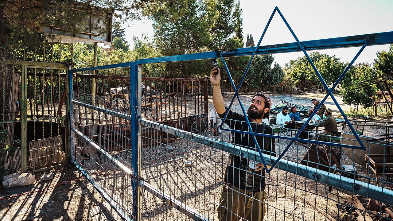 A Jewish settler paints the Star of David on newly installed gates after Jewish settlers forcibly took control of a property in Beit Jala, Occupied West Bank