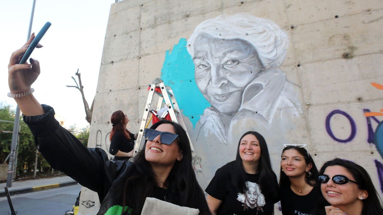 Young Lebanese women take a 'selfie' picture in front of a newly painted portrait of the late Egyptian writer and feminist Nawal el-Saadawi on a wall in the capital Beirut's downtown district.