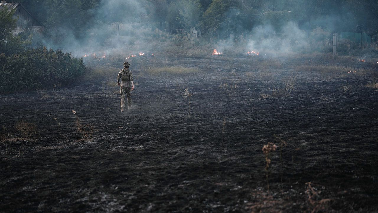 A Ukrainian soldier looks at artillery fire at the frontline in the Donetsk region