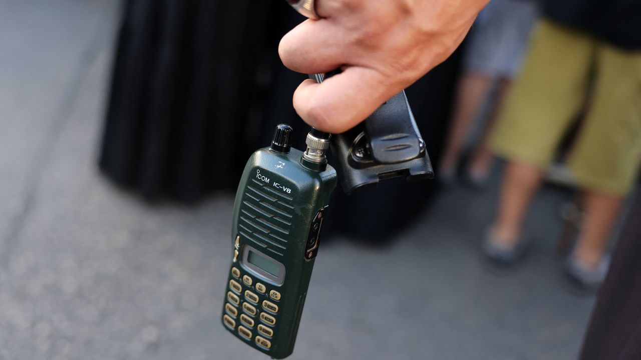 A man holds an Icom walkie talkie device after he removed the battery during the funeral of persons killed when hundreds of paging devices exploded in a deadly wave across Lebanon the previous day, in Beirut's southern suburbs.